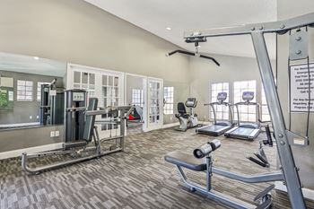 A gym with a variety of equipment including treadmills, weights, and a rowing machine.